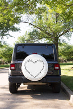 A white floral heart tire cover on a spare tire of a Jeep
